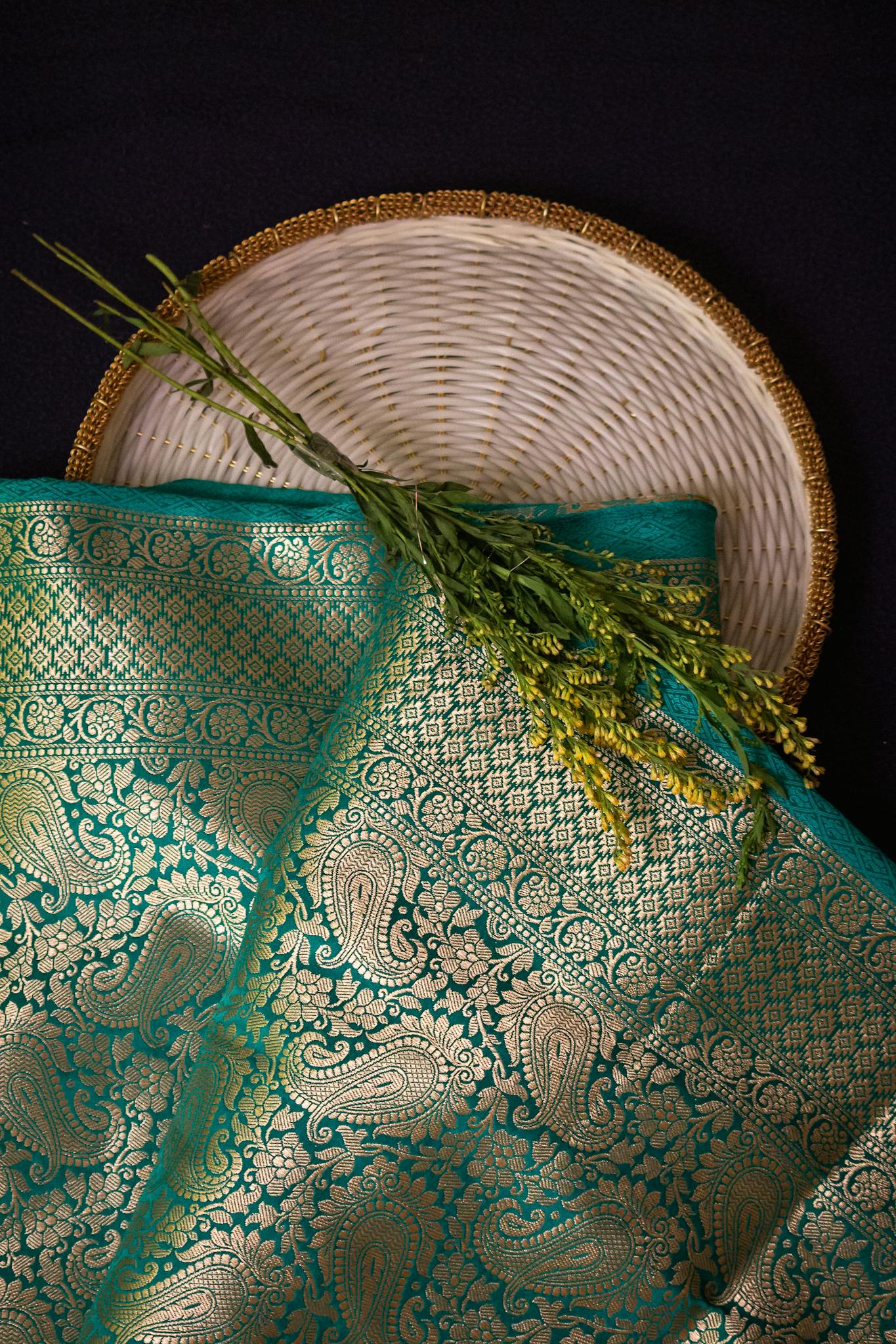 Close-up of a traditional Indian saree with intricate golden paisley patterns and floral decor.